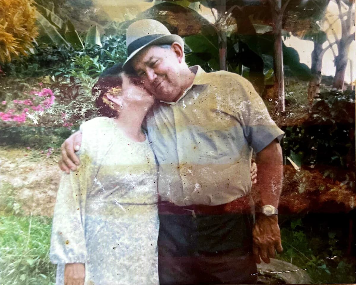 Fotografía antigua: una pareja mayor abrazada, al aire libre junto a la vegetación