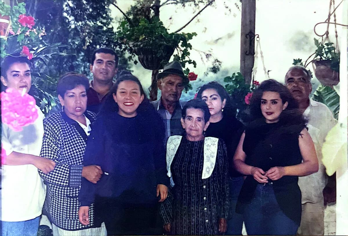 Fotografía antigua: un grupo familiar posando en el jardín, entre materas con flores